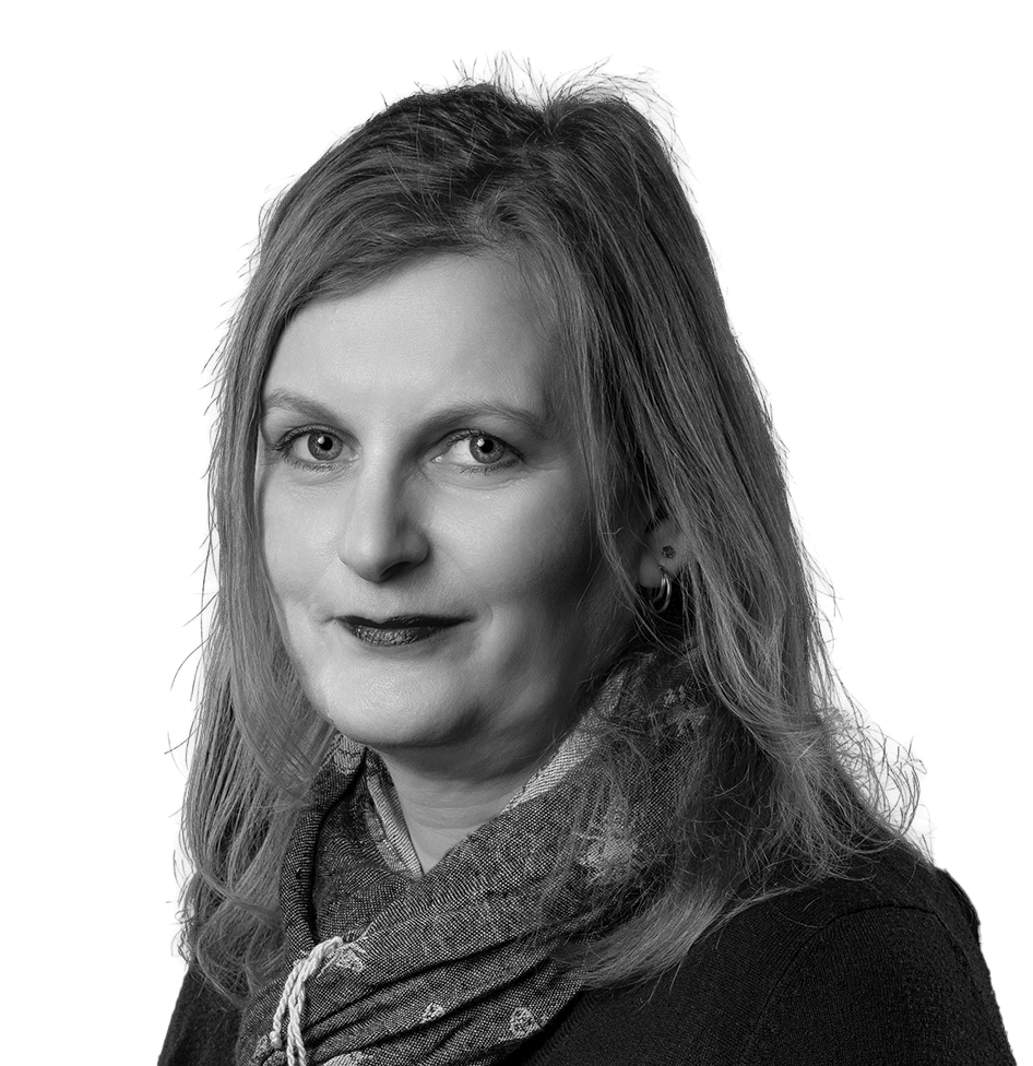 Black and white portrait of a woman with medium-length hair, wearing a patterned scarf and a dark top. She smiles softly at the camera against a black background.